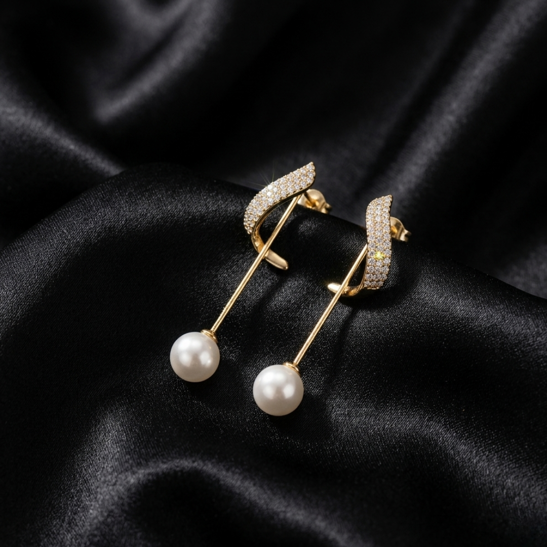Close-up detail of gold-plated wave pearl drop earrings with brilliant pave crystals displayed on black silk.