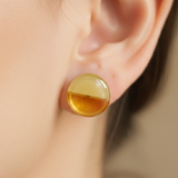 Close-up of Jwanas Amber Glow Dual-Tone Stud Earring worn on ear