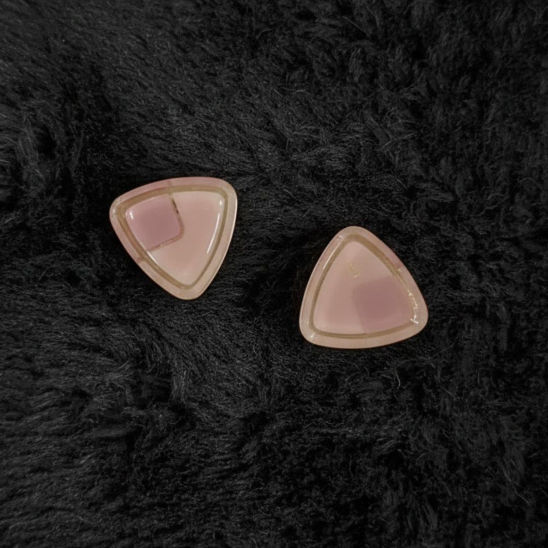Jwanas Blush Pink Triangle Stud Earrings flat lay on dark background