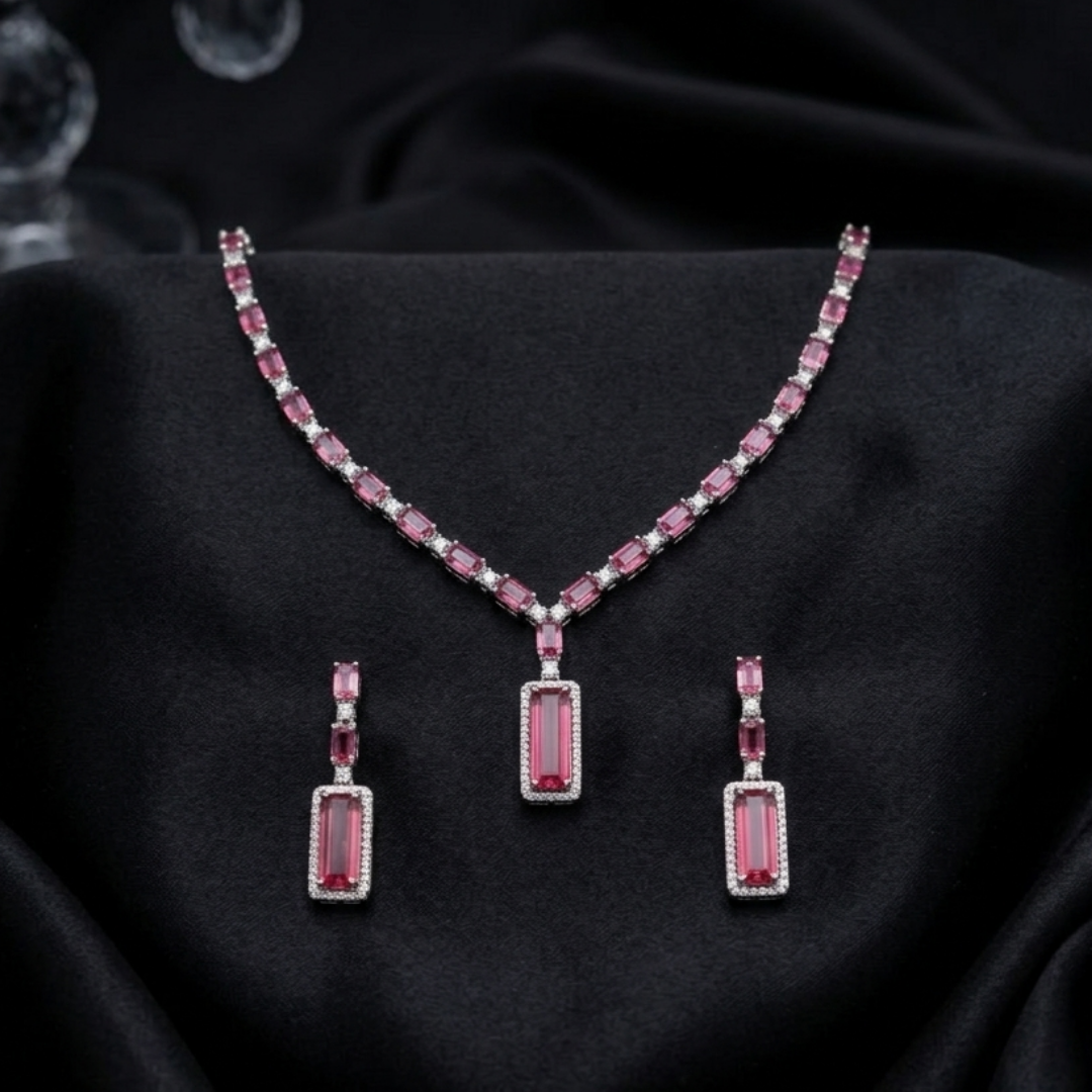 The Crimson Baguette Statement Set from Jwanas, necklace and earrings displayed on a black background