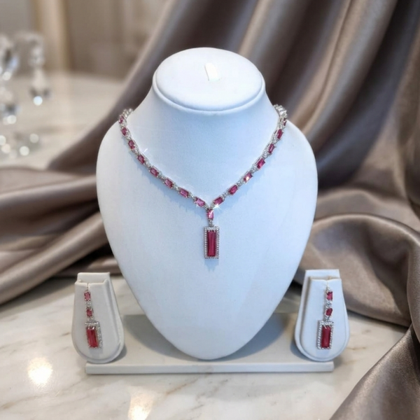 The Crimson Baguette Statement Set from Jwanas displayed on a white mannequin bust with matching earrings beside it