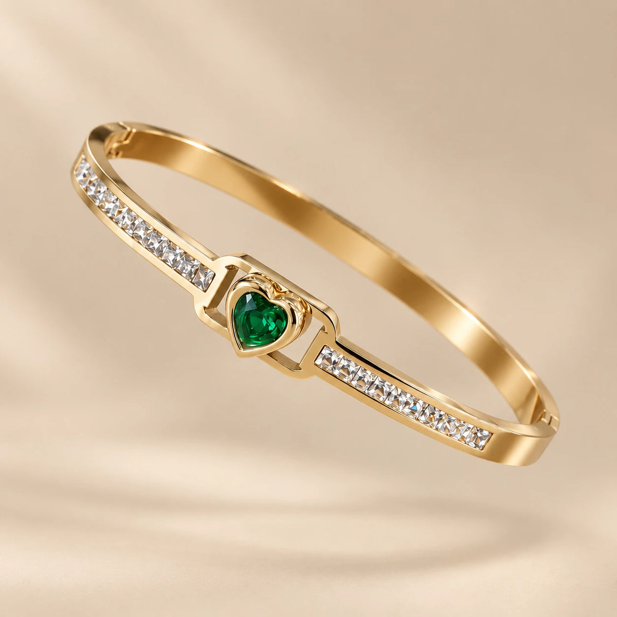 Close-up studio shot of the Jwanas Emerald-Green Heart Bangle Bracelet on a beige background