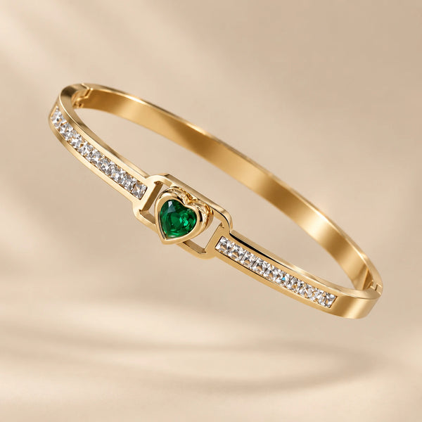 Close-up studio shot of the Jwanas Emerald-Green Heart Bangle Bracelet on a beige background