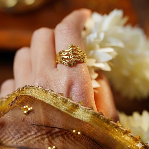 Close-up of a hand wearing the Jwanas Ethereal Wave Filigree Ring resting on a wooden surface