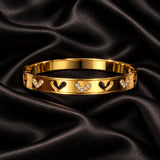 Jwanas Gold Heart Charm Bangle on black satin fabric