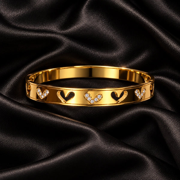Jwanas Gold Heart Charm Bangle on black satin fabric