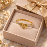 Jwanas Golden Bow Baguette Bangle Bracelet displayed inside an open gift box with a gold ribbon bow