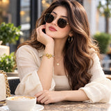 Model wearing the Jwanas Golden Bow Baguette Bangle Bracelet at a café table
