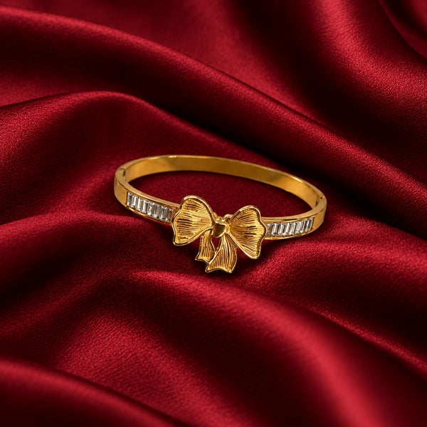 Jwanas Golden Bow Baguette Bangle Bracelet displayed on red satin fabric