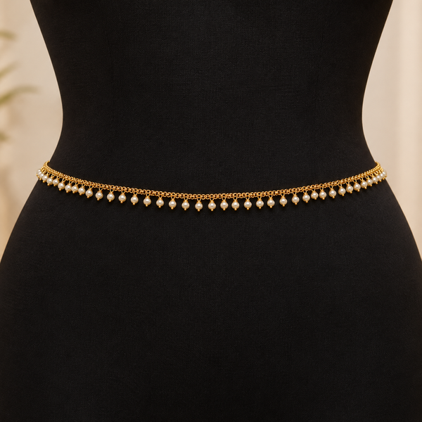 Jwanas Golden Pearl Elegance Waist Chain featuring a fine gold-tone chain and evenly spaced white pearl drops displayed on a black mannequin.