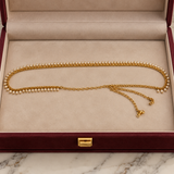 Jwanas Golden Pearl Elegance Waist Chain displayed in a cream-lined burgundy velvet jewellery box, featuring white pearl drops and an adjustable gold-tone chain.