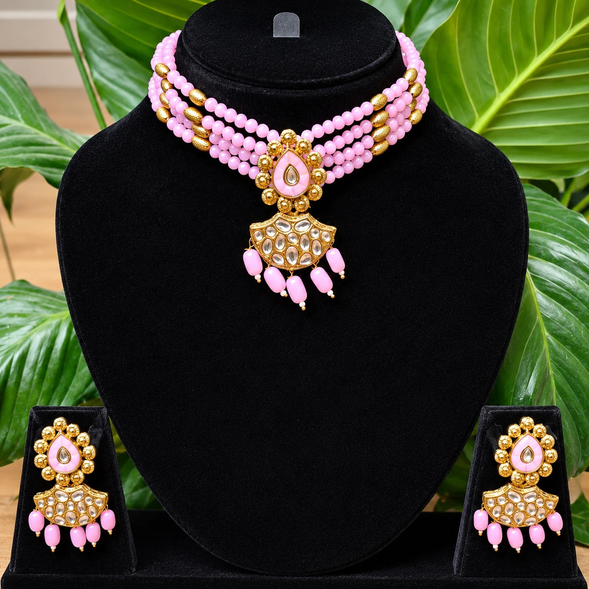 Jwanas Pink Blossom Beaded Choker Set displayed on a black bust stand with matching earrings, plant in background
