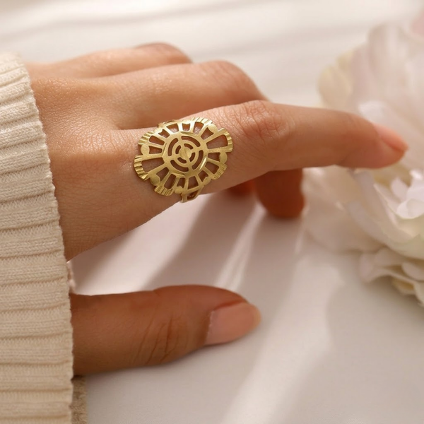 Close-up of a hand wearing the Jwanas Radiant Solar Mandala Ring against a light fabric background