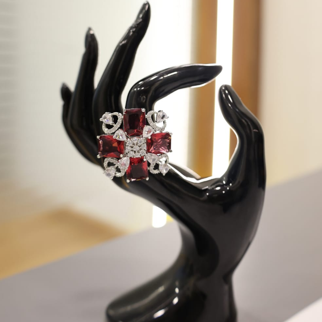 Jwanas Ruby-Red Floral Ring displayed on decorative hand prop
