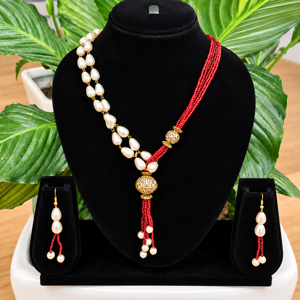 Jwanas Scarlet Pearl Cascade Necklace Set displayed on a black bust stand with matching earrings, plant in background
